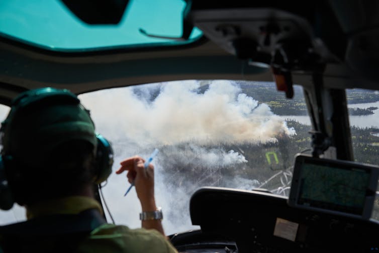 Wildfire smoke is seen from the cockpit of a helicopter.