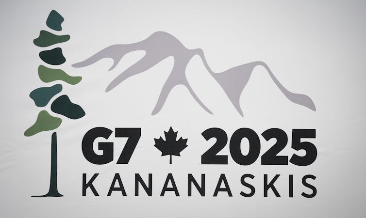 a G7 logo with mountains in the background and a tree in the foreground