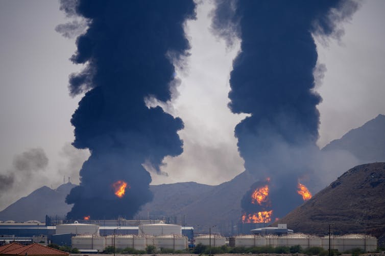 Large black plumes of smoke above two buildings in flames.