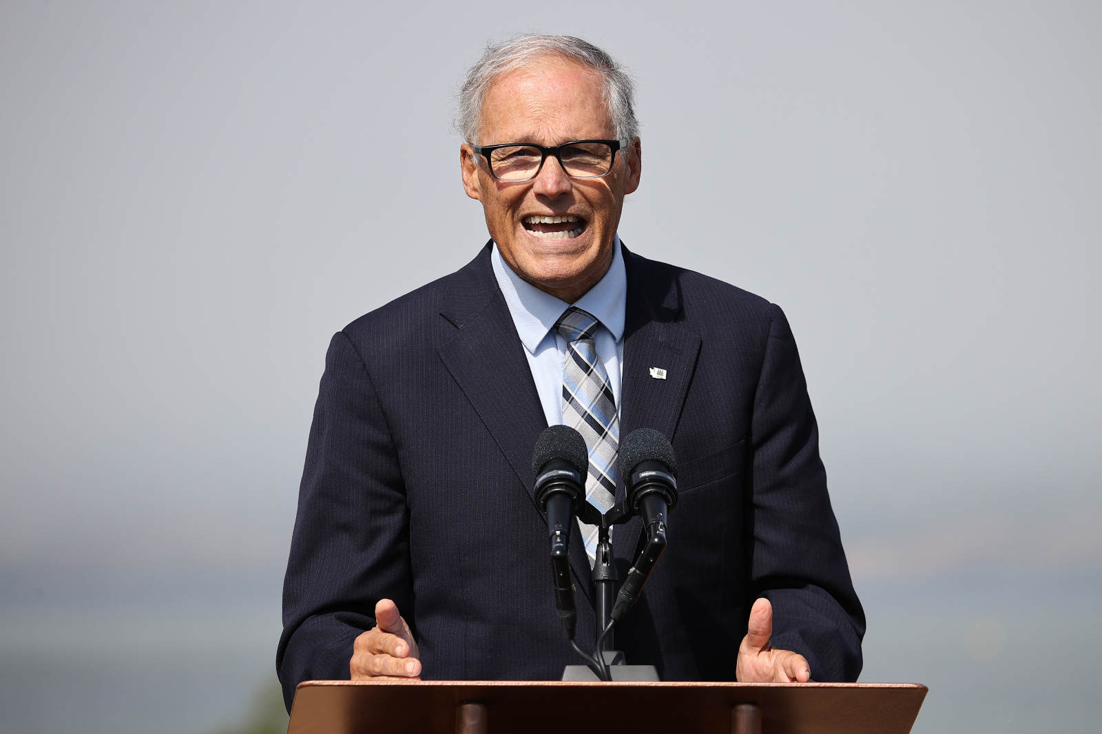 Photo of Jay Inslee speaking at a podium, with fog behind him